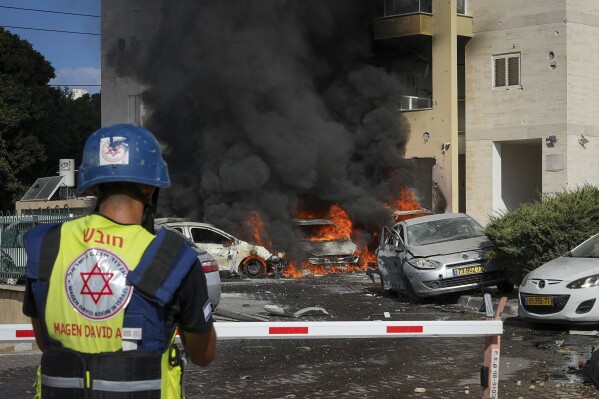 Cars burn after a rocket fired from the Gaza Strip hit a parking lot and a residential building in Ashkelon, southern Israel, Saturday, Oct. 7, 2023. The rockets were fired as Hamas announced a new operation against Israel. (AP Photo/Tsafrir Abayov)